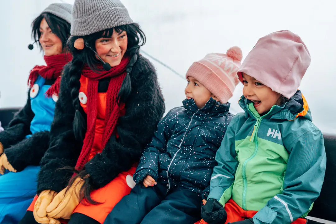 Two children sit with Trolle & Trolla in the gondola